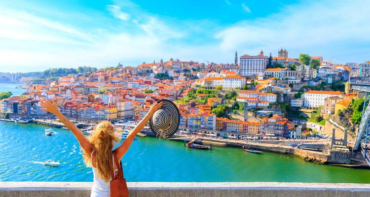Persona alzando los brazos con alegría contemplando una hermosa ciudad costera.