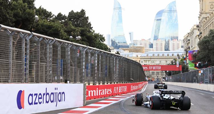 Autos de carrera en el Circuito Urbano de Bakú con edificios altos en el fondo.
