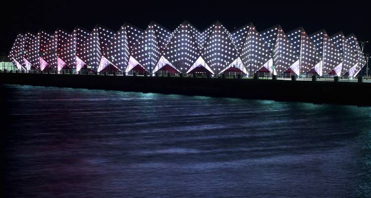 Estructura iluminada reflejándose en el agua por la noche.