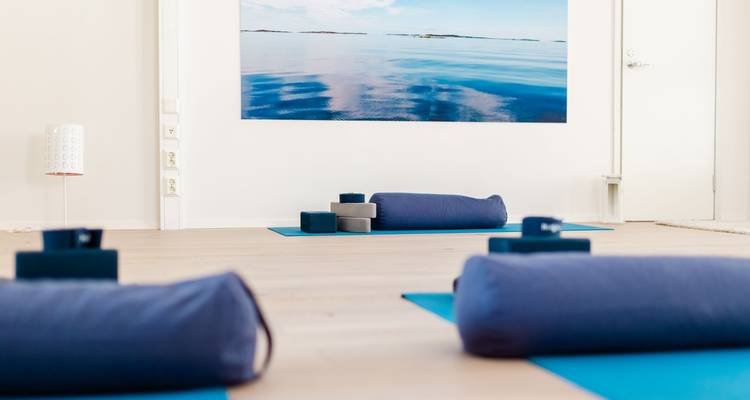 Vue intérieure d'un studio de yoga avec des tapis et des blocs disposés sur un plancher en bois.