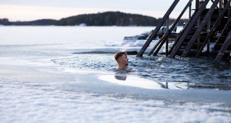 Personne nageant dans un trou de glace dans un lac gelé.