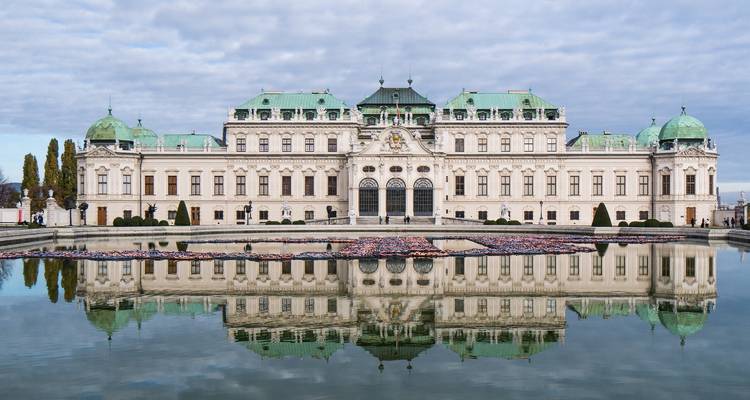Un palacio barroco histórico con un estanque al frente, reflejando parte de la estructura.