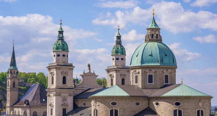Tejados de edificios europeos clásicos con montañas de fondo.