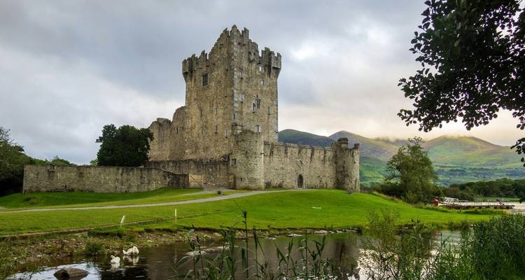 Château historique en pierre avec des montagnes en arrière-plan.
