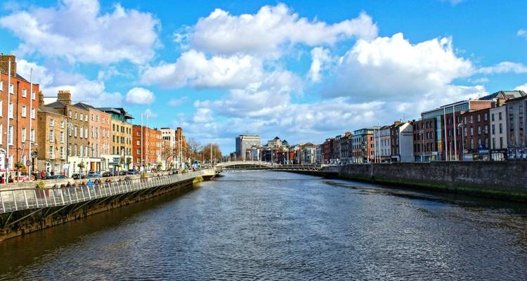 Vue sur la rivière dans la ville de Dublin avec des bâtiments de chaque côté sous un ciel bleu.