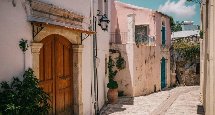 Encantador callejón con paredes de colores pastel y puertas de madera rústica, iluminado por la luz del día.
