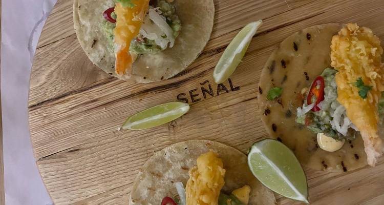 Tacos con gajos de lima en una tabla de madera, ofreciendo una experiencia culinaria única.