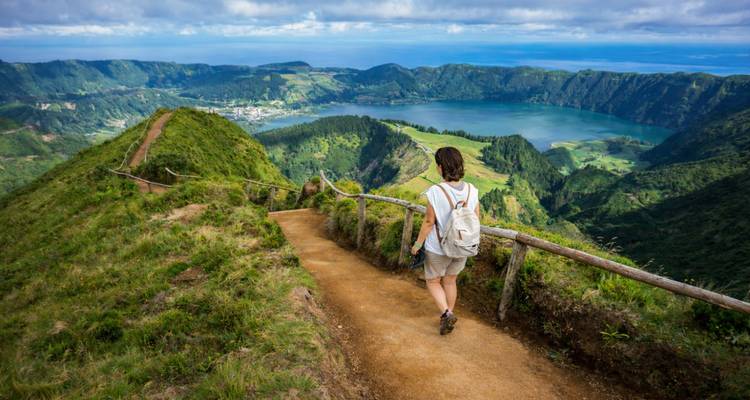Un randonneur avec sac à dos se promène le long du sentier de crête au-dessus de Sete Cidades avec des vues panoramiques sur le lac.