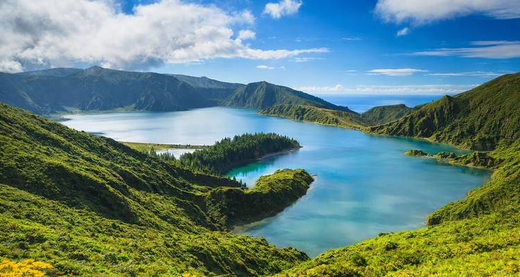La vive Lagoa do Fogo bleue se trouve au milieu de pics volcaniques verdoyants sous un ciel lumineux.