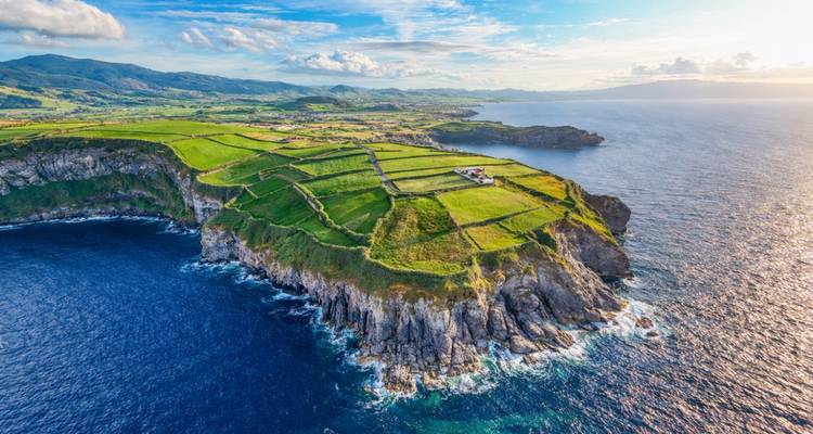 Une vue aérienne de champs verts en patchwork au sommet de falaises côtières spectaculaires qui s'avancent dans l'océan Atlantique.