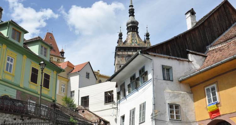 Escena callejera con fachadas históricas de colores y una torre del reloj al fondo.