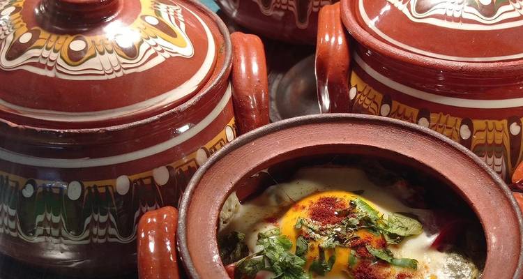 Ollas de barro tradicionales con un plato cocinado visible.