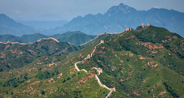 The Great Wall of China meandering over forested mountains.