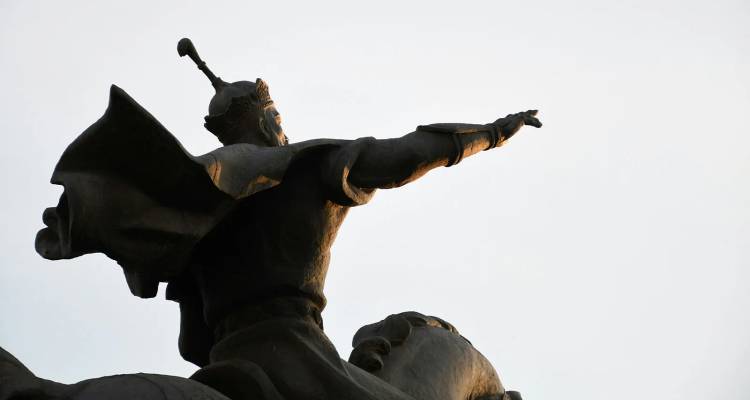 Estatua ecuestre de bronce recortada contra el cielo pálido, apuntando hacia la distancia