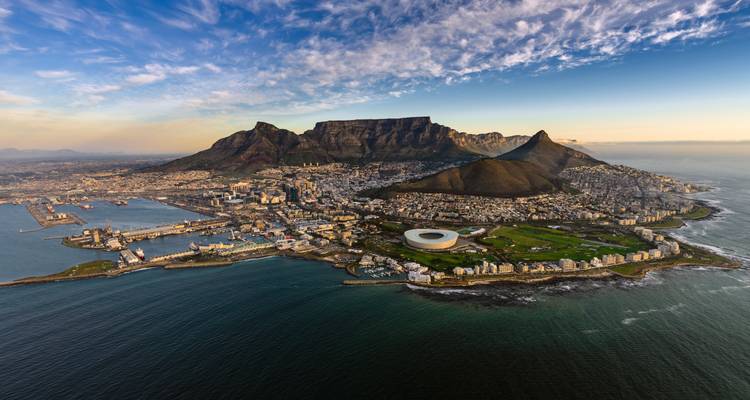 Aerial view of a coastal city with a classic stadium, scenic mountains and a coastline.