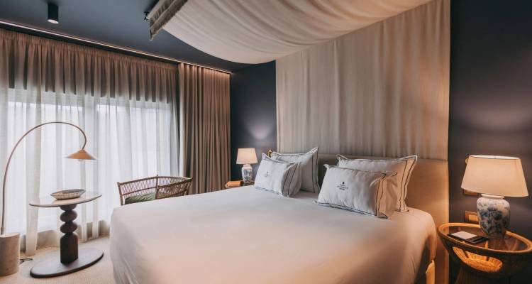 Chambre d'hôtel élégante avec plafond à baldaquin drapé, draps blancs impeccables et éclairage doux.