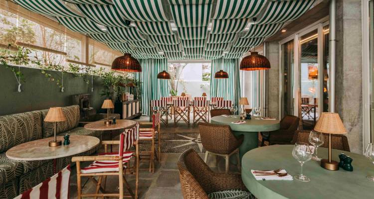 Intérieur de restaurant chic aux tons verts, plafond rayé et lampes en rotin.