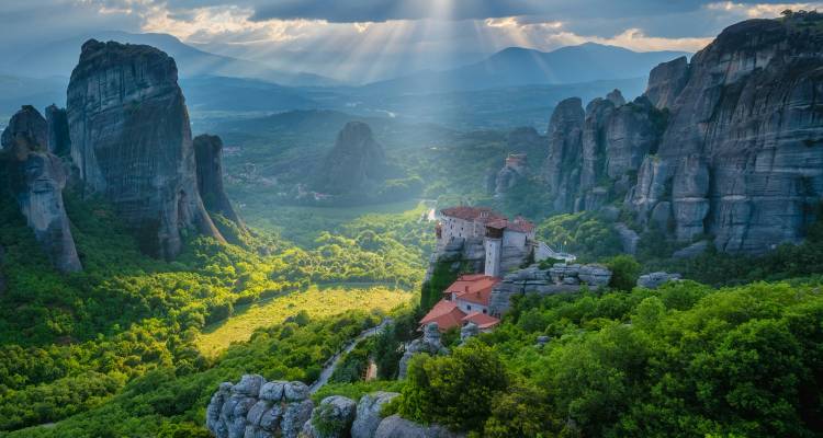 Meteora rotsformaties met een klooster genesteld tussen weelderig groen.