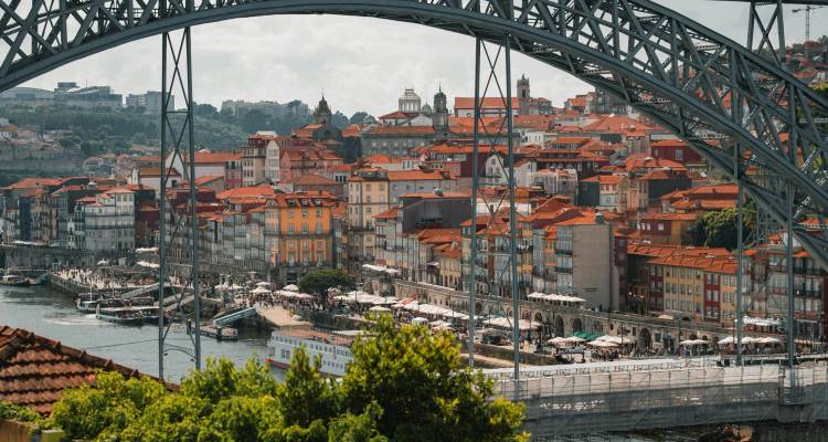 Un paysage urbain animé au bord de la rivière avec un pont imposant et une architecture historique.