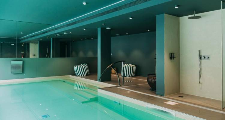 Piscina de spa cubierta moderna con agua turquesa y diseño minimalista