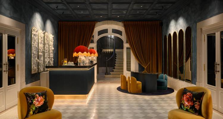 Elegante recepción del hotel con paredes oscuras, cortinas de terciopelo y asientos con estilo alrededor de una barra de recepción
