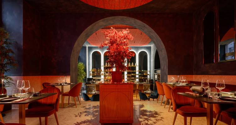 Interior elegante del restaurante con un arco dramático, centro de mesa con flores rojas e iluminación tenue