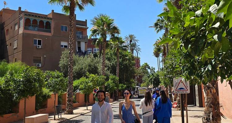 Straßenszene in Marrakesch mit Palmen und Menschen, die spazieren gehen.