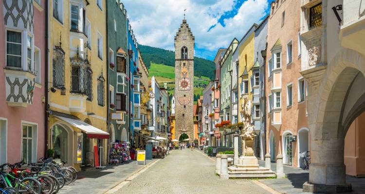 Calle peatonal con edificios coloridos y una torre del reloj.