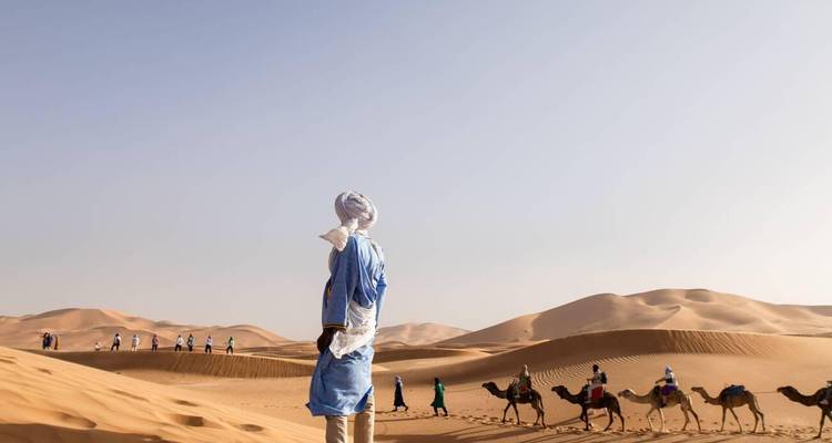 Caravana de camellos con jinetes en el desierto.