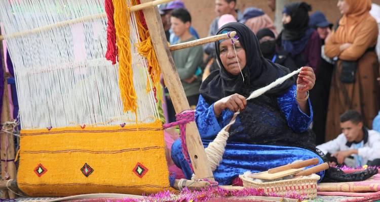 Mujer tejiendo tela tradicional al aire libre.