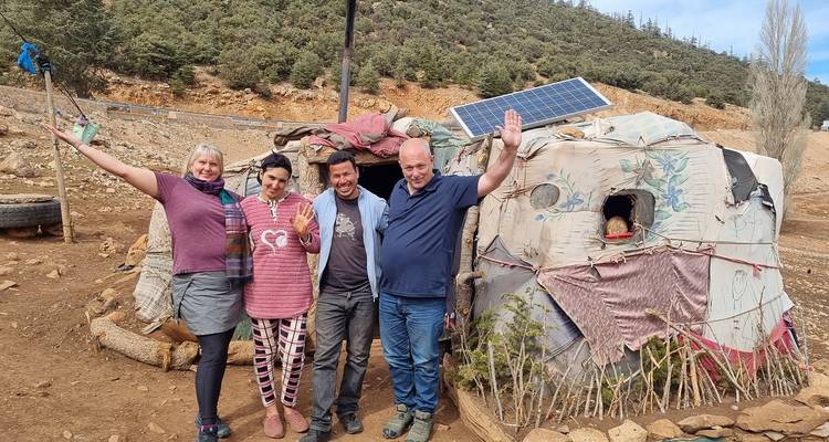 Grupo de personas posando frente a una vivienda rústica.