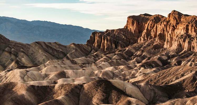 Formaciones rocosas estratificadas bajo un cielo brillante en el Valle de la Muerte.