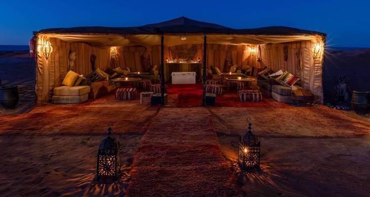 Camp luxueux dans le désert avec sièges confortables et lanternes