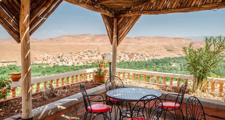 Table avec chaises donnant sur un paysage désertique et un village