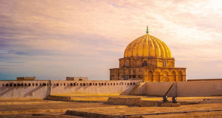 Sanctuaire au dôme doré au-dessus de murailles blanches sous la douce lumière du ciel.
