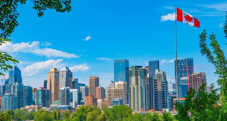 Horizon vibrant de Calgary avec le drapeau canadien flottant haut sous un ciel bleu éclatant