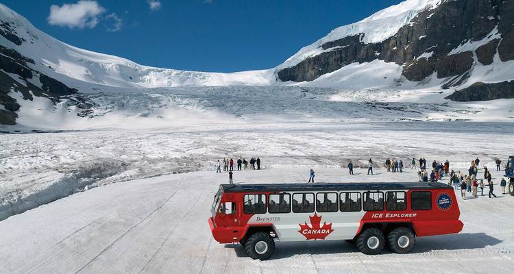 Grand bus Ice Explorer garé sur un vaste glacier avec des touristes se promenant au milieu de hautes parois de glace