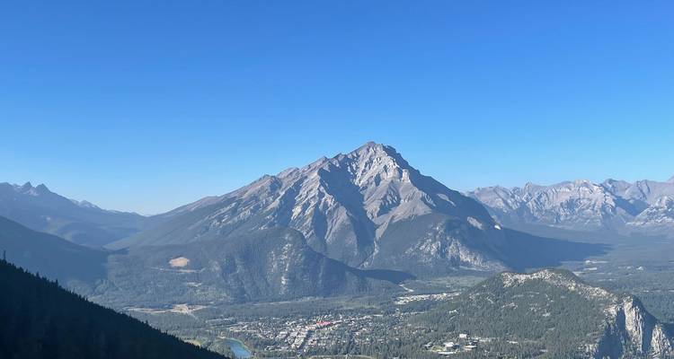 Vue lointaine d'un pic montagneux escarpé et accidenté qui domine la ville de Banff sous un ciel bleu dégagé
