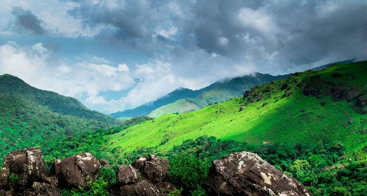 Vue panoramique de collines verdoyantes sous un ciel nuageux.