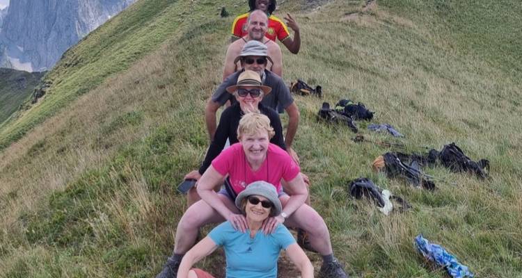 Gruppe von sechs Personen, die spielerisch auf einem Bergpfad posieren.