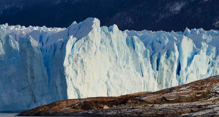 Majestuoso glaciar con un telón de fondo de montañas bajo cielos despejados.