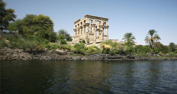 Ruinas de templo antiguo junto a un río con vegetación exuberante.