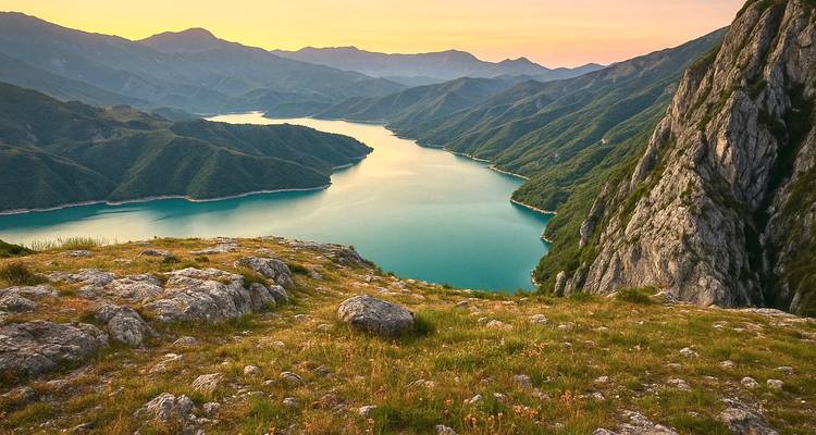 Coucher de soleil panoramique époustouflant sur un lac émeraude sinueux encadré par les luxuriantes montagnes albanaises.