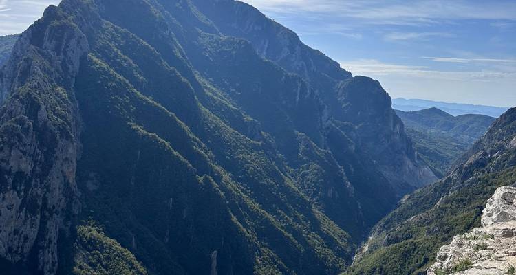 Des parois de canyon boisées et escarpées s'élèvent de façon spectaculaire sous un ciel albanais partiellement nuageux.