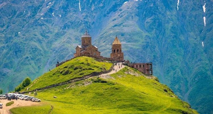 L'église de la Trinité de Gergeti perchée au sommet d'une colline verdoyante sous les imposants sommets du Caucase.