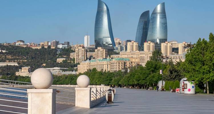 Promenade en bord de mer à Bakou avec les tours de la Flamme qui se dressent derrière le parc paysager.