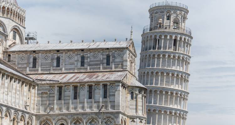 Vue rapprochée de la cathédrale de Pise et de son campanile penché contre un ciel bleu pâle.