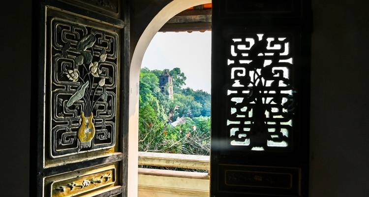 Une porte en bois décorative s'ouvre pour révéler une pagode lointaine nichée parmi les arbres verdoyants.