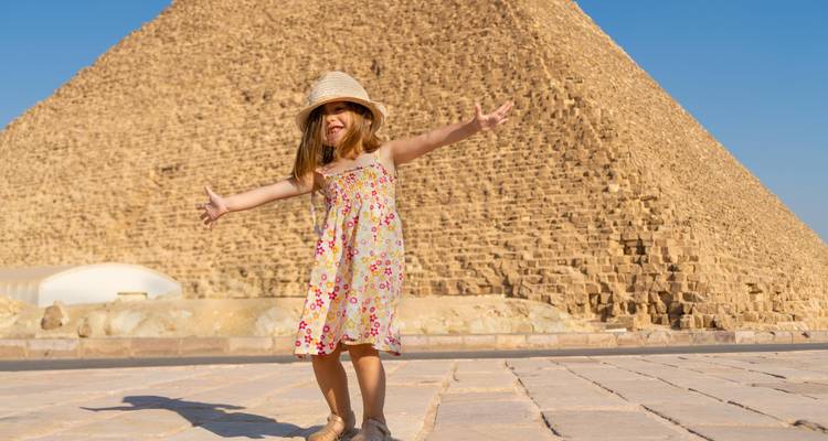 Niño posando felizmente frente a una gran pirámide.