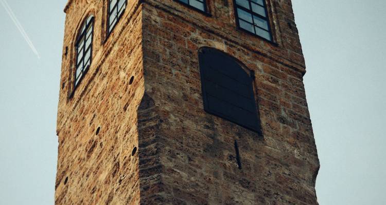 Gros plan d'une tour historique en pierre vue contre un ciel bleu.